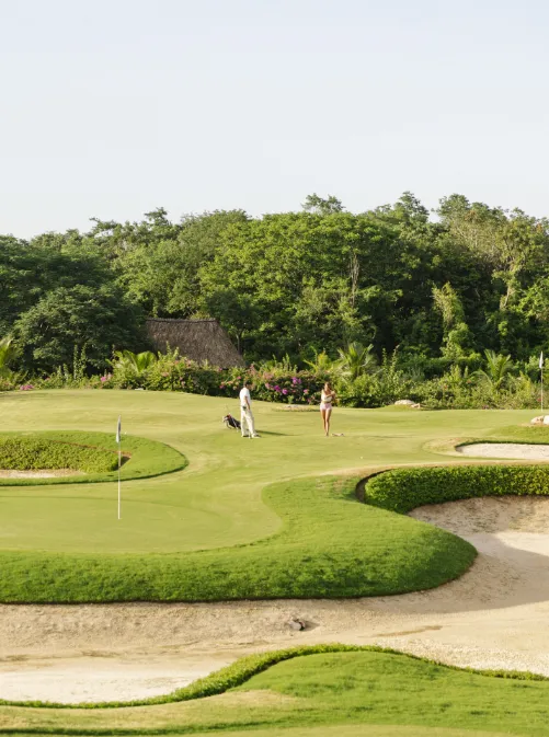 a couple of people on a golf course, a tilt shift photo by Juan Villafuerte, featured on pexels, land art, photo taken with ektachrome, playstation 5 screenshot, high dynamic range